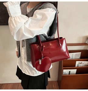 Detail of burgundy oil-wax leather tote bag with heart-shaped coin purse charm