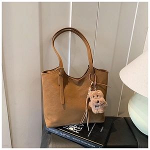 Détail du sac cabas caramel avec breloque ours en peluche et bandoulières
