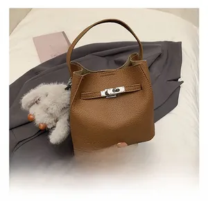 Close-up of brown pebbled leather bucket bag with silver twist lock and plush rabbit charm