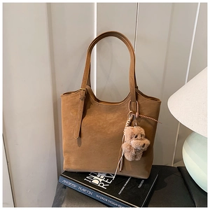 Détail d'un sac cabas en daim marron avec bandoulière réglable et breloque en peluche