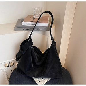 Détail du sac hobo en daim noir montrant la texture douce et le nœud latéral