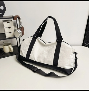 Detail of a black and white travel bag with durable woven handles and adjustable strap