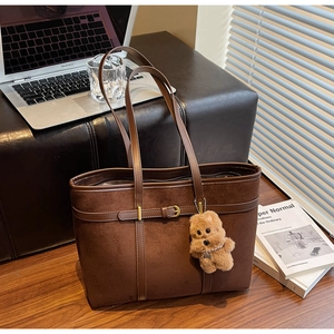 Detailed view of deep brown suede tote bag with metal buckle and plush bear charm