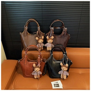 Four retro bucket bags in dark brown and black leather with cute bear charms on a sofa