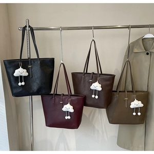 Collection of oversized leather tote bags in four colors with plush cloud charms on display