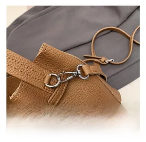 Close-up of silver D-ring and lobster clasp on brown lychee grain leather handbag
