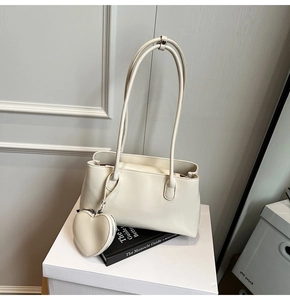 Detail of cream leather shoulder bag with matching heart charm and long strap design