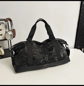 Detailed view of black waterproof travel bag with wrinkled texture on a white desk