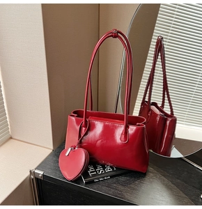 Glossy red leather tote bag detail with heart-shaped pouch and slim double straps