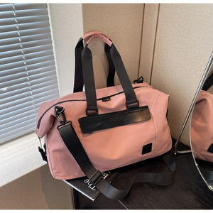 Detail of pink travel bag showing waterproof fabric, reinforced handles and metal hooks