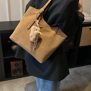 Détail du sac fourre-tout vintage marron avec breloque ours et boucle dorée réglable