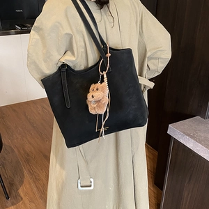 Sac fourre-tout en daim noir avec pendentif ours porté avec un trench-coat chic