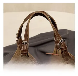 Detail of adjustable dark brown leather handles with silver metal buckles on a bucket bag