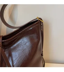 Close-up of dark brown leather tote with shiny gold adjustable metal hardware buckle