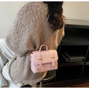 Close-up of pink crossbody bag with gold hardware and top handle on a female model