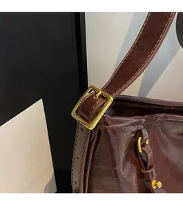 Close-up of golden metal buckle and glossy brown leather texture on a tote bag