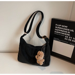 Detail of black Hobo tote bag featuring a cute brown plush bear charm and adjustable strap
