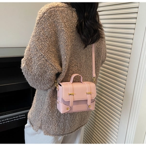 Detail of light pink mini square crossbody bag with gold hardware on a model