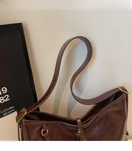Detail showing the brown leather texture and gold buckle of a large shoulder tote bag