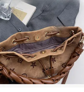 Detalle del bolso tipo saco con bordado floral, asa trenzada y cierre magnético dorado de lujo