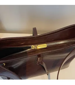 Detailed close-up of smooth gold zipper and oily waxed leather on vintage brown tote bag