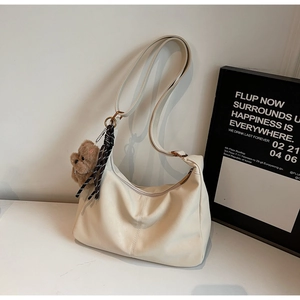 Detail of cream pleated tote bag with plush bear charm and striped ribbon accent
