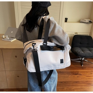 White waterproof travel bag with black straps and adjustable shoulder strap worn by a person