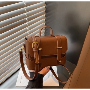 Close-up of vintage brown leather square bag featuring golden hardware and top handle