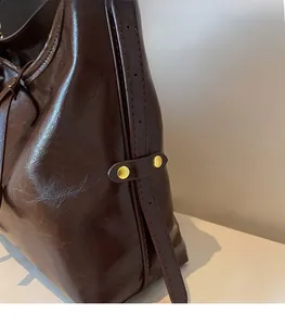Detail view of adjustable shoulder strap and gold rivets on dark brown leather tote