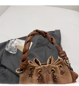 Detalle del bolso de lona marrón con bordado de estrellas y asa de cuero trenzado