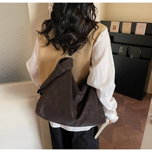 Sac hobo marron foncé en daim avec détail de bandoulière nouée porté par un modèle