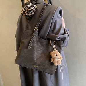 Détail du cabas en cuir marron foncé avec boucles dorées et breloque ours en peluche