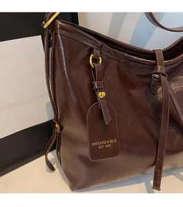 Close-up of deep brown oil-wax leather tote bag showing rich texture and gold hardware