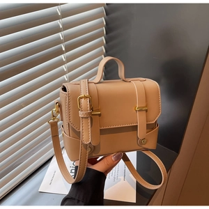Detail view of khaki square handbag with gold metal buckles and smooth vegan leather finish