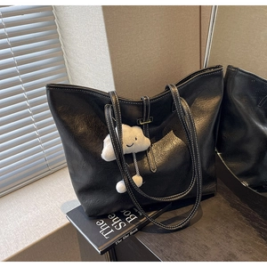 Detail of black tote bag with white contrast stitching and plush cloud pendant