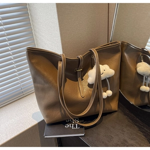 Close-up of deep brown tote bag with white contrast stitching and soft cloud charm