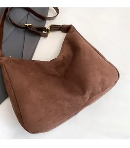 Detail of dark brown suede hobo bag with leather strap and golden buckle for commuting