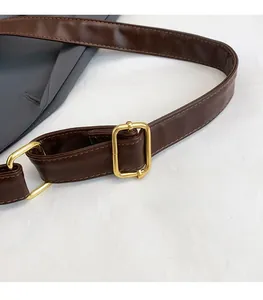 Detail of adjustable brown leather shoulder strap with golden metal buckle on tote bag