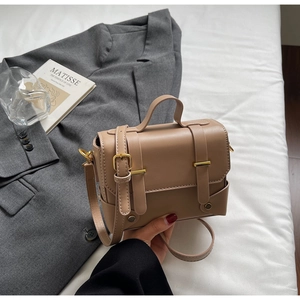 Minimalist khaki crossbody bag with top handle and metal buckle on white bedding