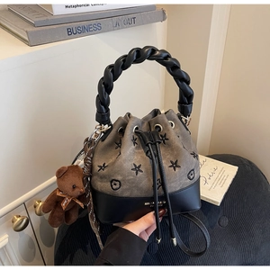 Detalle del bolso de lona gris pardo con estrellas bordadas y asa trenzada negra