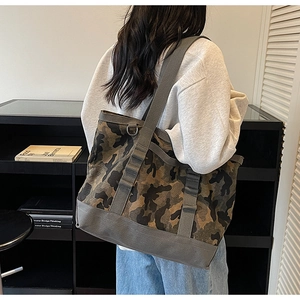 Détail du grand sac cabas en toile camouflage porté par un mannequin dans un bureau