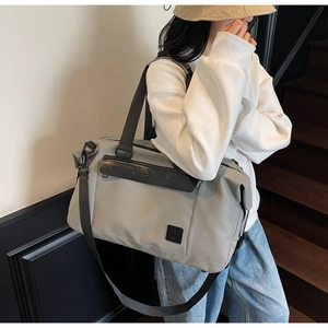 Adjustable shoulder strap and handle detail on a large grey travel duffel bag