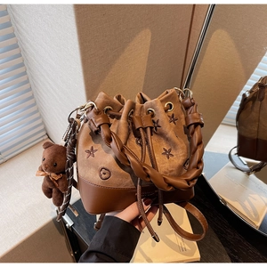 Detalle de bolso saco de lona con bordado floral y colgante de oso de peluche
