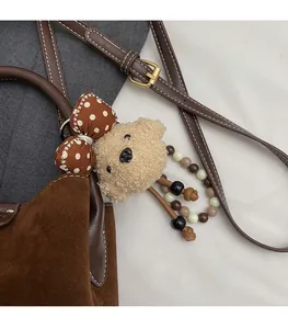 Primer plano de un colgante de osito de peluche con lazo de puntos en bolso marrón