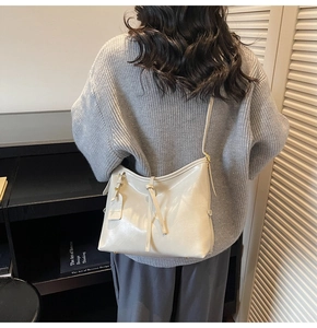 Detailed view of cream leather tote bag on shoulder featuring knotted strap decoration