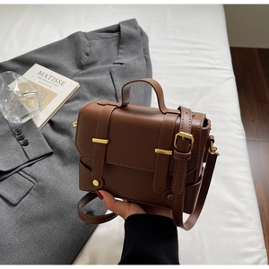 Detail of a brown vintage leather handbag with gold metal buckles and stitching details