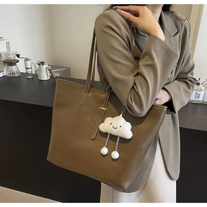 Close-up of brown faux leather tote bag with a white plush cloud charm for women