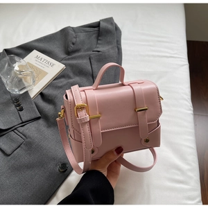Detail of pink faux leather crossbody bag with gold hardware and top handle design