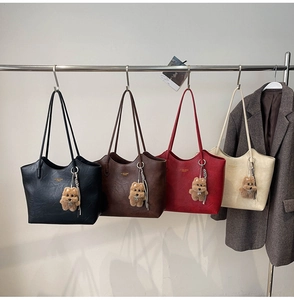 Detail of retro faux leather tote bags in four colors with plush bear charm hanging