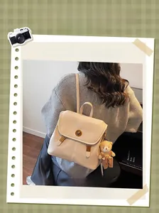 Macro detail of beige lychee texture leather backpack with gold clasp and bear charm